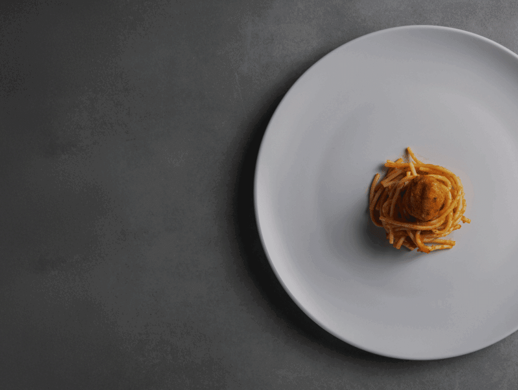 Small gourmet pasta on oversized white plate — symbolising profit margin imbalance in the hospitality industry