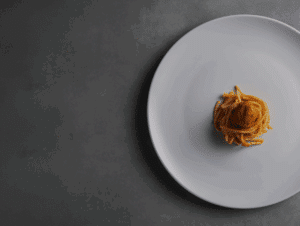Small gourmet pasta on oversized white plate — symbolising profit margin imbalance in the hospitality industry